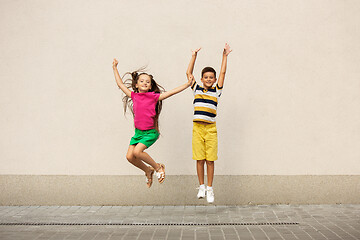 Image showing Two smiling kids, boy and girl running together in town, city in summer day