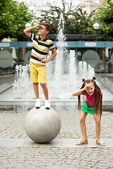 Image showing Two smiling kids, boy and girl running together in town, city in summer day