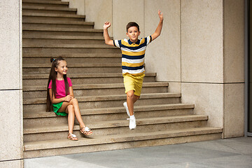 Image showing Two smiling kids, boy and girl running together in town, city in summer day