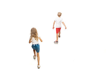 Image showing Happy little caucasian girl and boy jumping and running isolated on white background