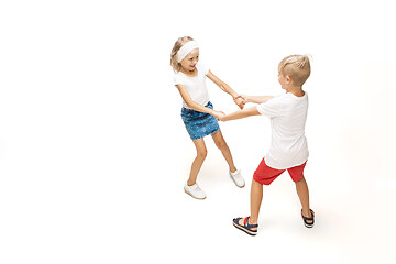 Image showing Happy little caucasian girl and boy jumping and running isolated on white background