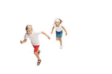 Image showing Happy little caucasian girl and boy jumping and running isolated on white background