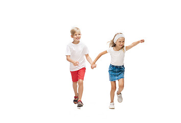 Image showing Happy little caucasian girl and boy jumping and running isolated on white background