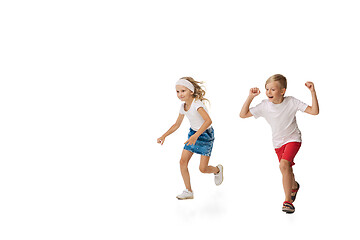 Image showing Happy little caucasian girl and boy jumping and running isolated on white background