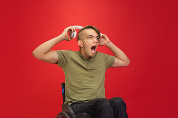 Image showing Caucasian young man\'s portrait isolated on red studio background. Human emotions concept