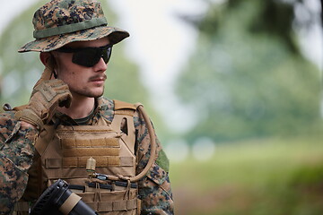 Image showing soldier preparing tactical and commpunication gear for action ba