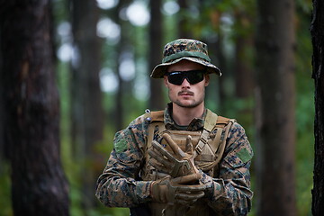 Image showing soldier preparing tactical and commpunication gear for action ba