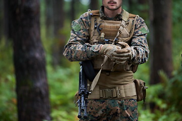 Image showing soldier preparing tactical and commpunication gear for action ba