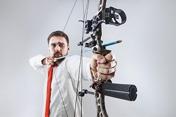 Image showing Businessman aiming at target with bow and arrow, isolated on white background