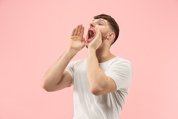 Image showing Isolated on pink young casual man shouting at studio