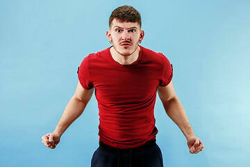 Image showing The young emotional angry man screaming on blue studio background