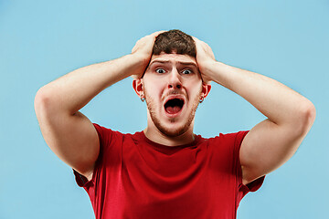 Image showing The young emotional angry man screaming on blue studio background