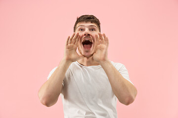 Image showing Isolated on pink young casual man shouting at studio