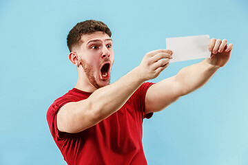 Image showing Young boy with a surprised expression bet slip on blue background