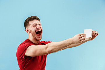 Image showing Young boy with a surprised expression bet slip on blue background