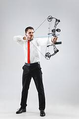 Image showing Businessman aiming at target with bow and arrow, isolated on white background