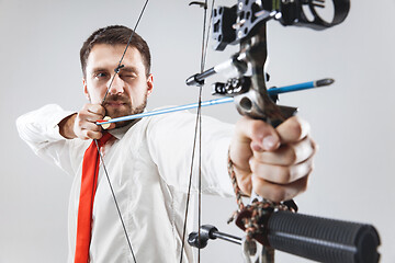 Image showing Businessman aiming at target with bow and arrow, isolated on white background