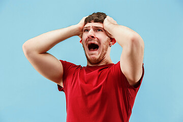 Image showing The young emotional angry man screaming on blue studio background