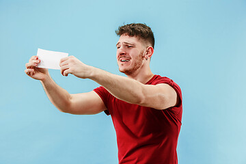 Image showing Young boy with a surprised expression bet slip on blue background