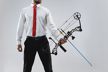 Image showing Businessman aiming at target with bow and arrow, isolated on white background