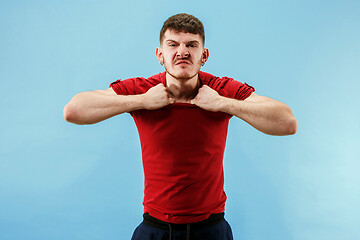 Image showing The young emotional angry man screaming on blue studio background