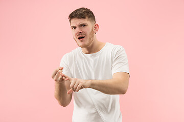 Image showing Beautiful male half-length portrait isolated on pink studio backgroud. The young emotional surprised man