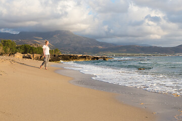 Image showing Woman walking on sand beach at golden hour