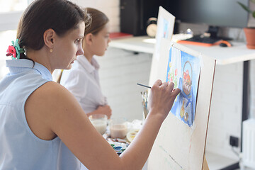 Image showing Girl sits next to the child and paints still life