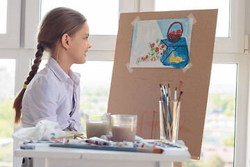 Image showing The girl happily looks at her finished drawing hanging on an easel