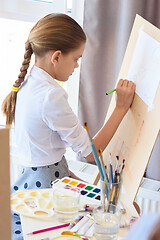 Image showing Girl is focused on drawing with a pencil on an easel