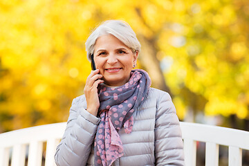 Image showing senior woman calling on smartphone at autumn park