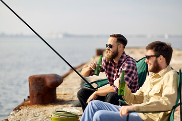 Image showing happy friends fishing and drinking beer on pier