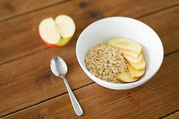 Image showing oatmeal in bowl with apple and spoon on table