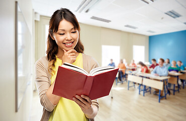 Image showing happy asian woman reading book at school