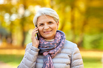 Image showing senior woman calling on smartphone at autumn park