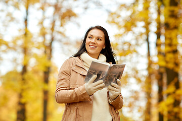 Image showing happy young woman with city guide in autumn park