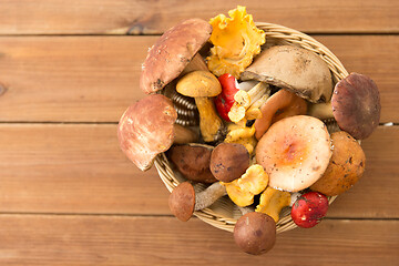 Image showing basket of different edible mushrooms on wood