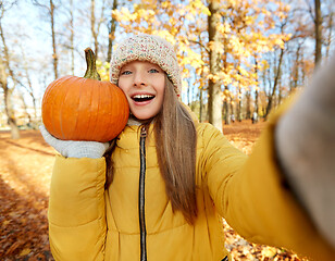 Image showing girl with pumpkin taking selfie at autumn park