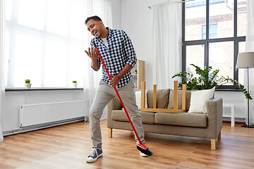 Image showing man with broom cleaning and singing at home