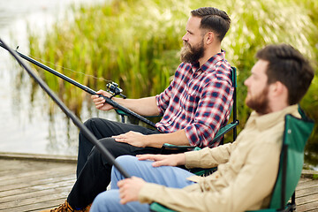 Image showing friends with fishing rods at lake or river