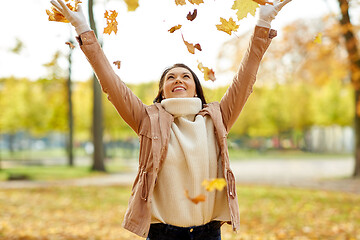 Image showing happy woman having fun with leaves in autumn park