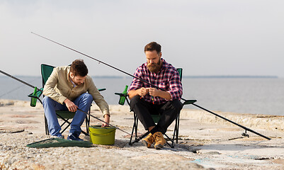 Image showing friends adjusting fishing rods with bait on pier