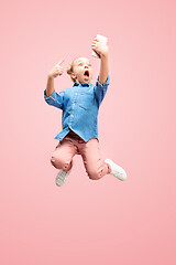 Image showing Young happy caucasian teen girl jumping with phone in the air, isolated on pink studio background.