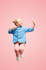 Image showing Young happy caucasian teen girl jumping with phone in the air, isolated on pink studio background.