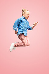 Image showing Young happy caucasian teen girl jumping with phone in the air, isolated on pink studio background.