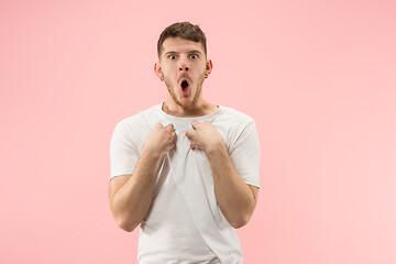 Image showing Beautiful male half-length portrait isolated on pink studio backgroud. The young emotional surprised man