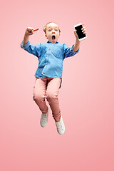 Image showing Young happy caucasian teen girl jumping with phone in the air, isolated on pink studio background.