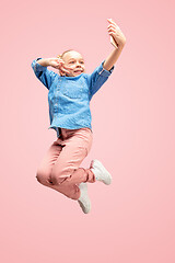 Image showing Young happy caucasian teen girl jumping with phone in the air, isolated on pink studio background.