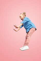 Image showing Young scared caucasian teen girl jumping in the air, isolated on pink studio background.