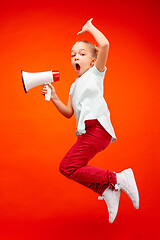 Image showing Beautiful young child teen girl jumping with megaphone isolated over red background